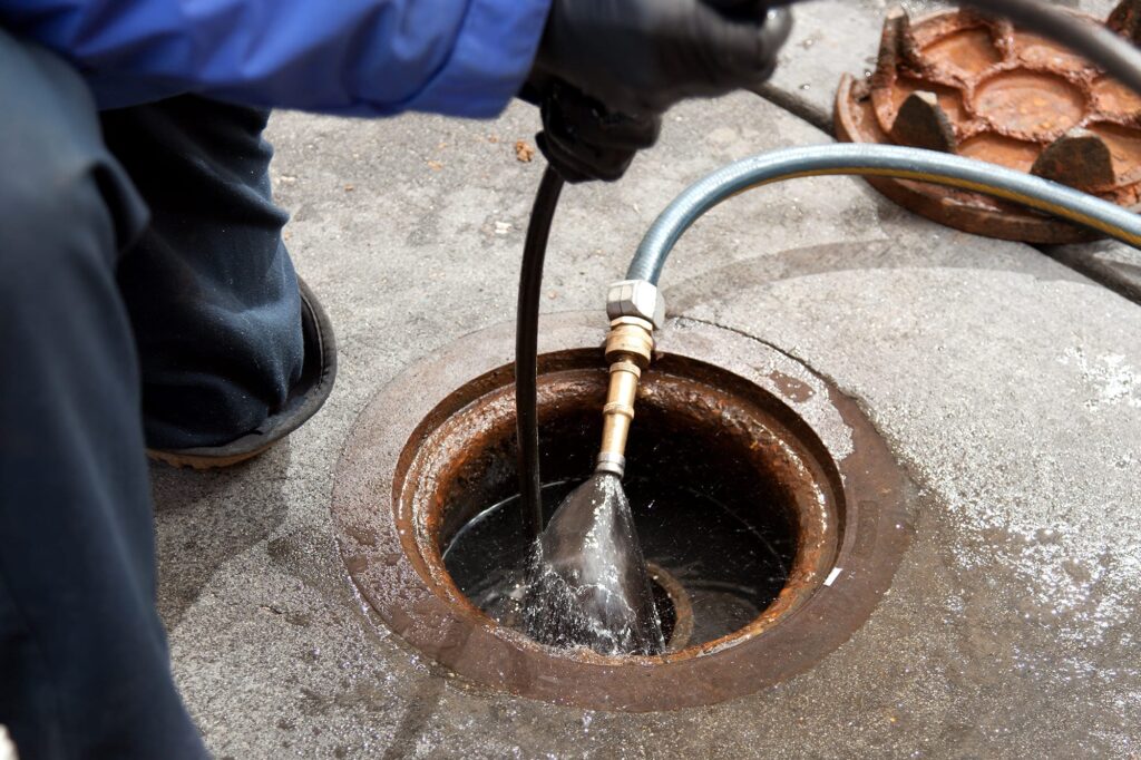 Plumber hydro jetting a sewer line through a manhole in Castle Rock