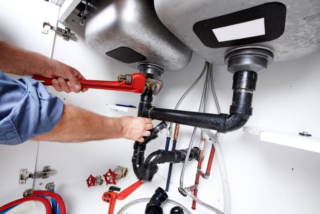 Plumber repairing drain pipes beneath a kitchen sink in Castle Rock