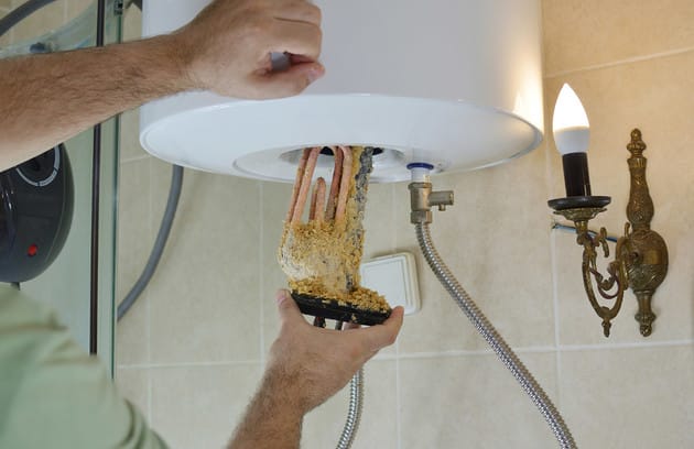 Technician removing mineral buildup from a water heater in Castle Rock