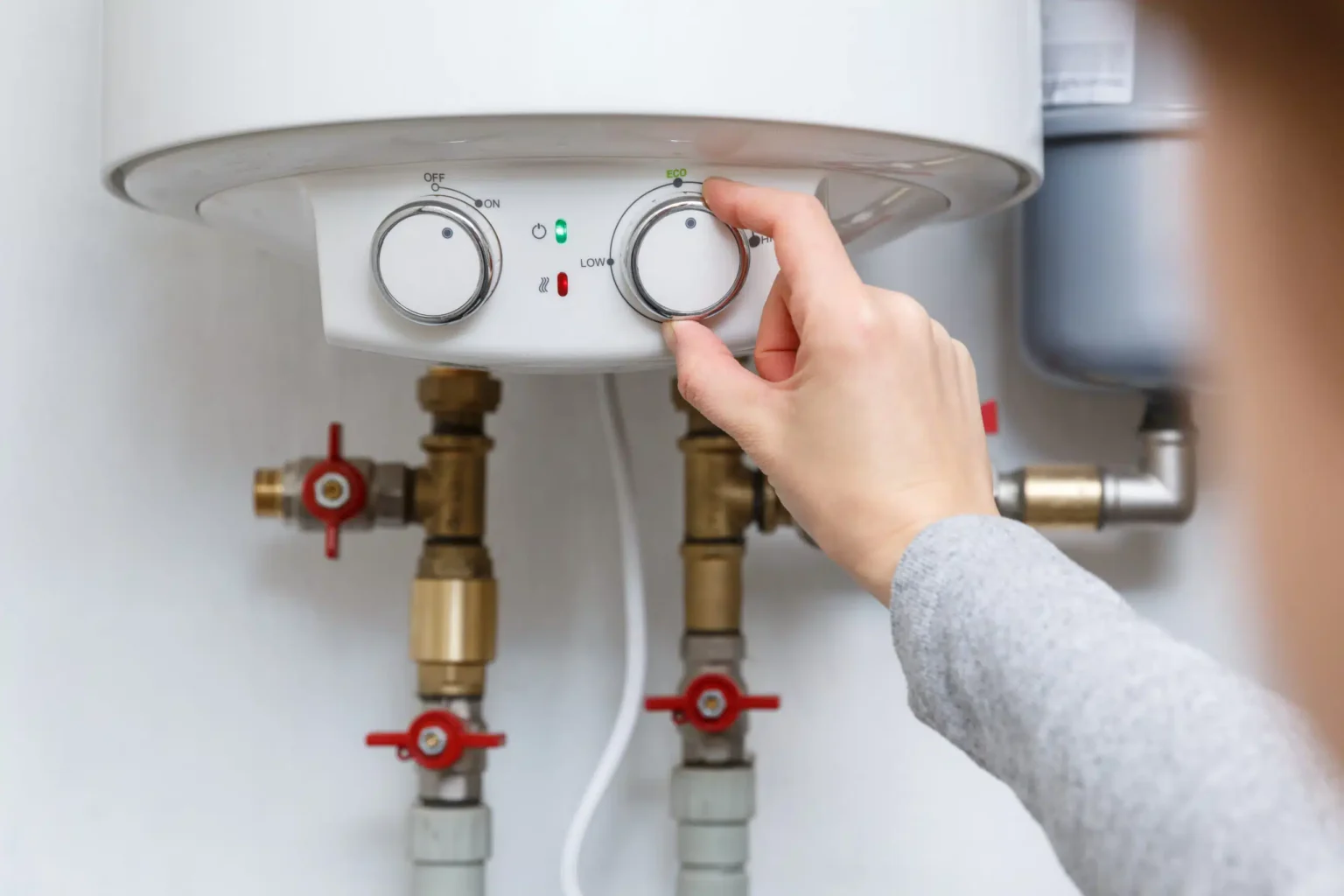Homeowner adjusting the temperature controls on a water heater in Castle Rock